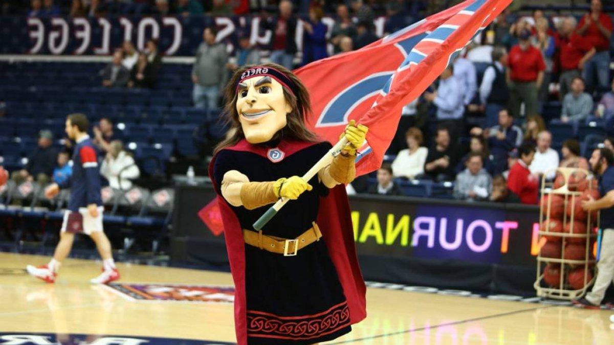Gideon the SMC mascot running across the basketball court holding a flag